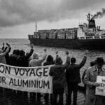Humor. Satire. Noir. Black and white. A crowd sadly waves goodbye and Bon Voyage to a freighter full of aluminium cans as it turns around and heads away across one of the Great Lakes.
