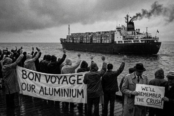 Humor. Satire. Noir. Black and white. A crowd sadly waves goodbye and Bon Voyage to a freighter full of aluminium cans as it turns around and heads away across one of the Great Lakes.