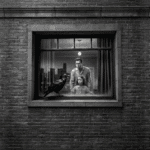 A jet black raven perches on a windowsill in front of a man and little girl. Noir